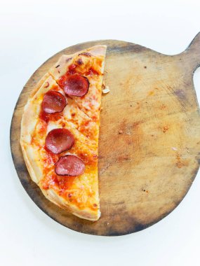 Eritilmiş mozzarella peynirli ve altın hamurlu bir pepperonili pizza kırsal ahşap servis tahtasının üzerinde sunuluyor..