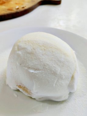 Sütlü kremalı çöreğe yakın. Tabakta şeker tozu var.