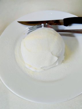 Beyaz tabakta servis edilen şekerli pudra şekerli yastıklı Asya sütlü çörek.