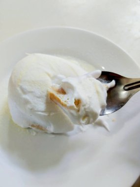 Beyaz bir tabaktan kaşıkla yumuşak ve kremalı Asya sütlü çörekler.