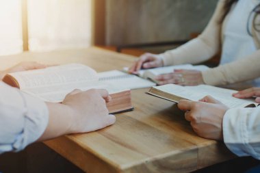 Bir grup Hıristiyan ahşap masanın etrafında oturuyorlar. Bulanık İncil sayfası açıp birlikte Tanrı 'ya dua ediyorlar.