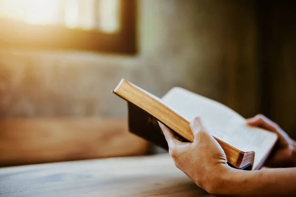 Pencere ışığı, kriz çözeltisi olan ahşap masa üzerinde kitap tutan ve okuyan bir kadın Tanrı 'ya, Hristiyan inancına, güvene ve itaat eden, fotokopi alanı ile sabah sadakati kavramına dua eden bir kadın.