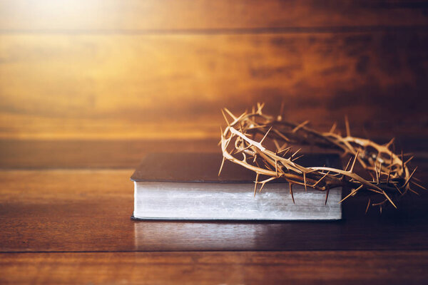 Close up of the crucifix of Jesus Christ over an old holy bible on wooden table. Good Friday or Easter concept with copy space