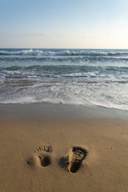 Kumda çıplak ayak izleri var. Denize doğru gidiyorlar. Gelen dalgayı bekliyorlar.