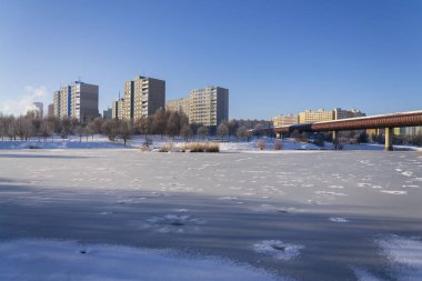 Ağaçların arkasındaki izole paneldeki evler, yüksek katlı apartmanlar, beton levhalardan prefabrik bloklar, büyük panel binası, enerji verimliliği binası konsepti, soğuk hava güneşli kış günü.