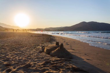 Gün batımında sahilde güzel bir kumdan kale, çocuklar yaratıcılık, aktif tatil konsepti.