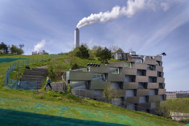 Amager Slope ya da Kopenhill olarak bilinen Amager Bakke 'nin çatısındaki insanlar, eğlence tesisi ile enerji santraline ısı ve enerji atıklarını birleştirerek, 1 Mayıs 2023' te Danimarka 'nın Kopenhag kentinde kuru kayak pisti, yürüyüş pisti ve tırmanma duvarı oluşturdular..