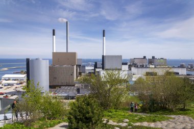 People in public space on the roof of Amager Bakke known as Amager Slope or Copenhill, combined heat and power waste to energy plant with recreational facility - dry ski run, hiking trail and climbing wall on May 1, 2023 in Copenhagen, Denmark. clipart