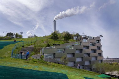 People in public space on the roof of Amager Bakke known as Amager Slope or Copenhill, combined heat and power waste to energy plant with recreational facility - dry ski run, hiking trail and climbing wall on May 1, 2023 in Copenhagen, Denmark. clipart