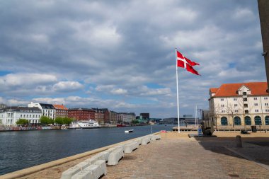 A waving Danish flag on a pole on the waterfront in the center opposite the famous Nyhavn clipart