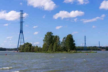 Blue power line poles running from the seashore across the island to the mainland, global energy crisis, renewable energy and grid stability concept clipart