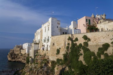 Adriyatik denizinden yükselen dramatik kayalıklardaki geleneksel evler, Polignano 'daki Lama Monachile a Mare, İtalya