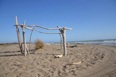 Yıkanmış odunlar, İtalya 'da Marina di Grosseto yakınlarındaki kumsalda rüzgar ve güneşe karşı ahşap barınaklar inşa edilirdi.