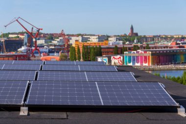 Göteborg şehir merkezi arka planda, İsveç, yenilenebilir yeşil sürdürülebilir enerji kavramı ile apartman binasının çatısında güneş panelleri