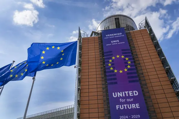 20 Mayıs 2025 'te Belçika' nın Brrussels kentinde Avrupa Komisyonu genel merkezinin önünde AB bayraklarını sallayan.