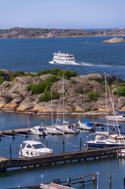 Alvsborgsfjorden, Alvsborg ilçesi, Göteborg, İsveç, güneşli bir günde Saltholmen yarımadasındaki gemilerle birlikte limandan kalkan takımada feribotu.