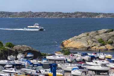 13 Mayıs 2025 'te İsveç' in Göteborg şehrinde Alvsborgsfjorden, Alvsborg bölgesinde bulunan Saltholmen yarımadasındaki gemilerle birlikte limandan kalkan takımada feribotu..