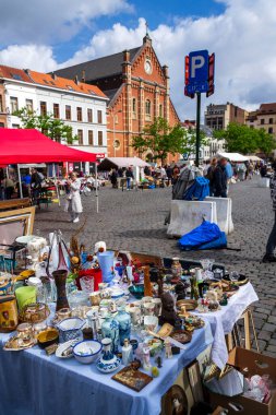 İnsanlar 26 Mayıs 2026 'da Brüksel, Belçika' da, Place du Jeu de Balle 'de, arka planda bulunan Meryem Ana Kilisesi' nde bitpazarından eski antika şeyler satın alıyorlar..