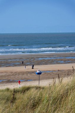 Kum tepelerinin yakınındaki güzel kumsaldaki insanlar Batı Flanders, güneşli yaz günü 23 Mayıs 2025, De Haan, Belçika.