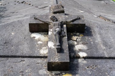 Crucifix on grave at an abandoned Dieweg cemetery overtaken by nature in Brussels, Belgium, sunny day
