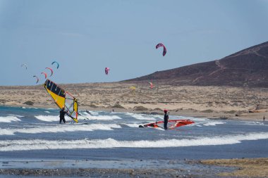 İnsanlar 7 Temmuz 2019 'da İspanya' nın El Medano şehrinde Granadilla de Abona belediyesinde Playa de Leocadio Machado plajında sörf, uçurtma ve rüzgar sörfü yapıyorlar..