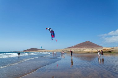 İnsanlar 7 Temmuz 2019 'da İspanya' nın El Medano şehrinde Granadilla de Abona belediyesinde Playa de Leocadio Machado plajında sörf, uçurtma ve rüzgar sörfü yapıyorlar..