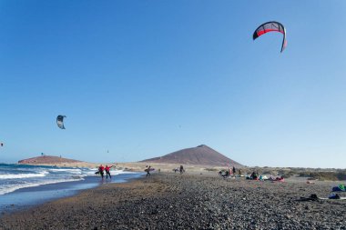 İnsanlar 8 Temmuz 2019 'da İspanya' nın El Medano şehrinde Granadilla de Abona belediyesinde Playa de Leocadio Machado plajında sörf, uçurtma ve rüzgar sörfü yapıyorlar..