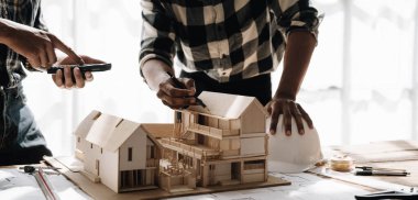 Mimarlar, takım mühendisi elinde kalem tutan ekipman mimarları ofiste bir planla birlikte masanın üzerinde, Vintage, Sunset Light. Seçici Odaklanma.