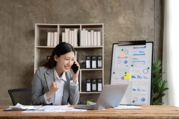 Pretty Asian businesswoman sitting on a laptop And the work came out successfully and the goal was achieved, happy and satisfied with her..