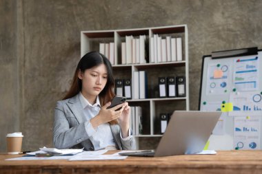 Asyalı bir kadın online problem çözümü hakkında çok endişeli. Laptop ekranına bakıyor. Asyalı ciddi iş kadını zor bir bilgisayar işini çözmeye odaklanmış...
