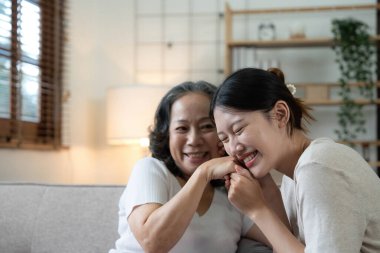 Mutlu yetişkin torun ve büyük anne sohbetten zevk alıyor modern oturma odasındaki koltukta oturuyor, gülümsüyor yaşlı anne genç yetişkin kızı kucaklıyor.