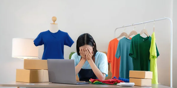 Woman seller SME retail store owner work hard worry stress in bad news on laptop at home office desk. Asian people crisis tailor job issue feel tired tough and upset in cash money loss or loan debt..