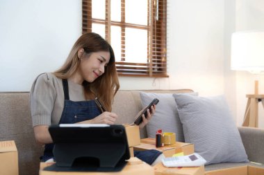 Girişimci KOBİ küçük işletme girişimcisi kadın telefon görüşmesi yaparak müşteriden hisse senedi üzerinde ürün kontrol etme, çevrimiçi pazarlama paketleme dağıtım kutusu alımı