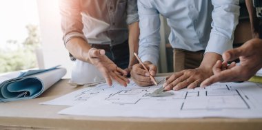 İnşaat mühendisi takımları modern kentteki inşaat sahasında birlikte çalışan işçi kaskı takıyorlar. Foreman sektörü proje yöneticisi mühendislik takım çalışması