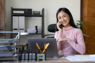 Gülümseyen Asyalı iş kadını. Çizelgeyi ve grafiği analiz ediyor. Piyasadaki değişiklikleri gösteriyor....