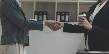 Ofiste iki Asyalı iş kadını el sıkışıyor. İş birliği, iş anlaşması, tebrikler, selamlaşma. Görüntüyü kapat.