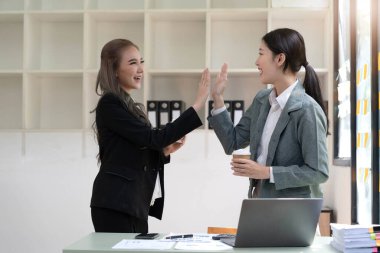 Genç Asyalı iş adamları yaratıcı iş adamları ofiste başarılı iş arkadaşları başarıyı ve başarı kavramını kutlayan ortaklık çalışmalarından mutluluk duyarlar.