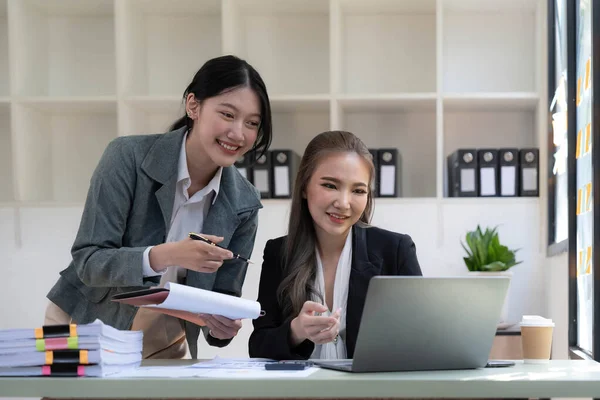 stock image Two young Asian business woman talk, consult, discuss working with new startup project idea presentation analyze plan marketing and investment in the office...