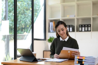 İş yerinde dizüstü bilgisayarda çalışan Asyalı genç bir iş kadınının portresi. İş adamları serbest internet üzerinden pazarlama e-pazarlama kavramını rapor ediyor.