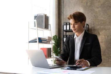 Ofiste dizüstü bilgisayarla çalışan genç bir iş adamı. Asyalı işadamı işyerinde oturuyor.