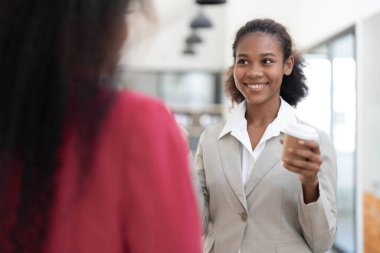 Sırıtkan iş arkadaşları birlikte dizüstü bilgisayarda çalışan, ekrana bakan, ofiste masa başında duran, proje stratejisini tartışan, fikirleri paylaşan iş kadınları..