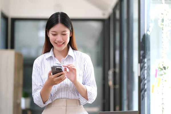 stock image Portrait of elegant successful asian business woman speaking by smartphone and smiling happily while standing against window in office