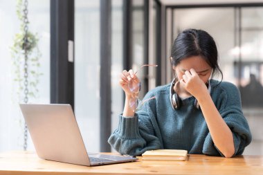 Evde dizüstü bilgisayarla çalışan stresli bir kadın endişeli, yorgun ve bunalmış görünüyor....