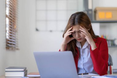 Asyalı bir kadın online problem çözümü hakkında çok endişeli. Laptop ekranına bakıyor. Asyalı ciddi iş kadını zor bir bilgisayar işini çözmeye odaklanmış...