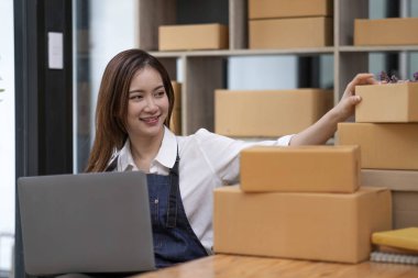 Küçük bir girişimin portresi, bir KME sahibi, bir Asyalı bayan girişimci ürünleri müşterilerle birlikte iç kutulara koymadan önce ürünleri düzenlemek için siparişleri kontrol ediyor. Serbest kavramlar..