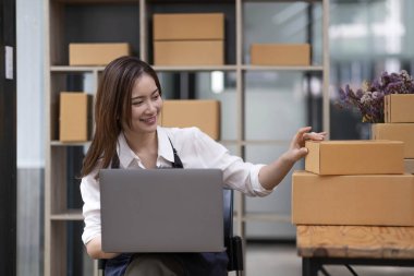 Küçük bir girişimin portresi, bir KME sahibi, bir Asyalı bayan girişimci ürünleri müşterilerle birlikte iç kutulara koymadan önce ürünleri düzenlemek için siparişleri kontrol ediyor. Serbest kavramlar..