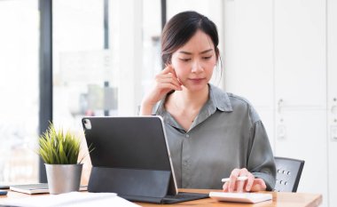 Asyalı iş kadını iş yerinde çok ciddi. Ofiste dizüstü bilgisayarlı belgelerle başağrısı yaratıyor....