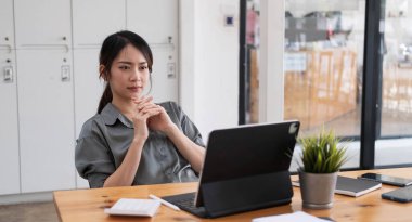 Asyalı iş kadını iş yerinde çok ciddi. Ofiste dizüstü bilgisayarlı belgelerle başağrısı yaratıyor....