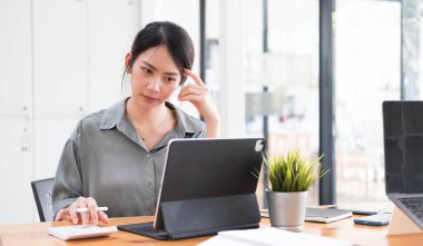 Asyalı iş kadını iş yerinde çok ciddi. Ofiste dizüstü bilgisayarlı belgelerle başağrısı yaratıyor....