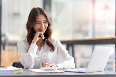 Ofiste dizüstü bilgisayarda çalışan genç bir kadın. Ofisteki iş yerinde oturan Asyalı iş kadını. Güzel Freelancer Kadını evinde çalışıyor.